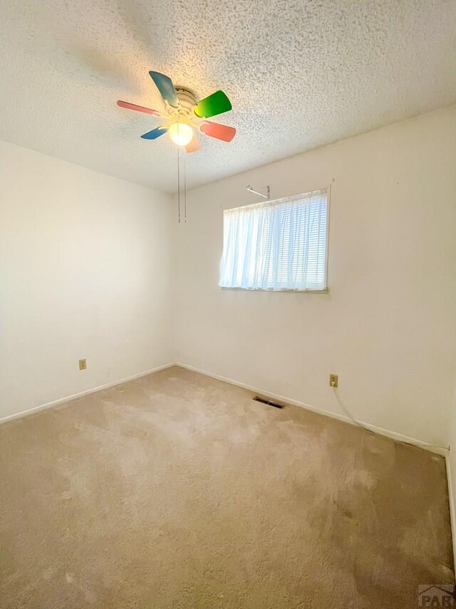 carpeted spare room featuring a textured ceiling, visible vents, and baseboards