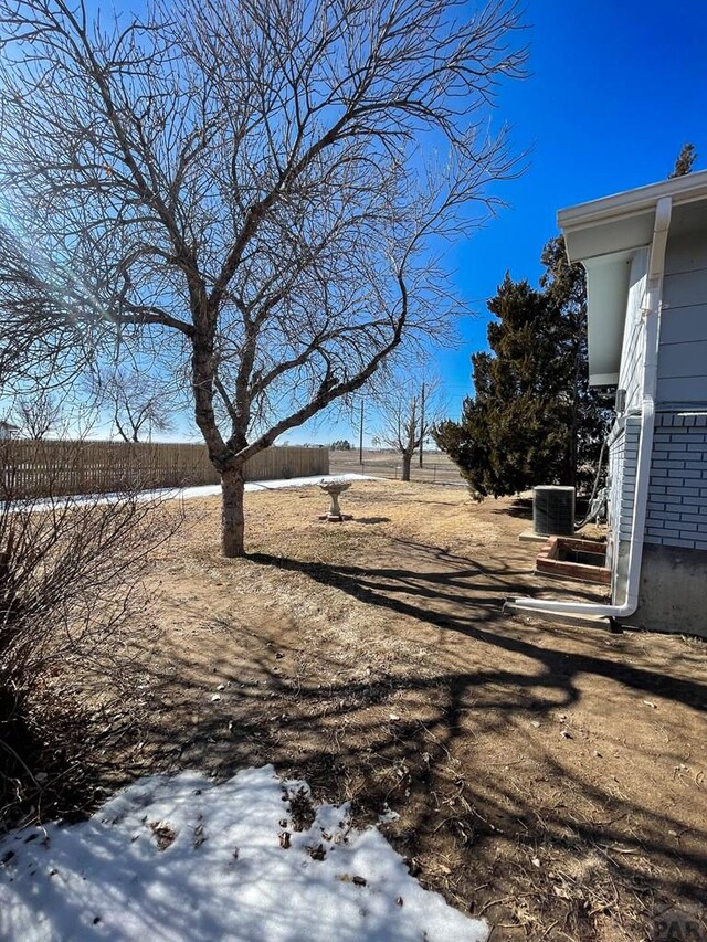 yard covered in snow featuring fence and cooling unit