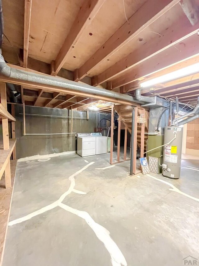 unfinished below grade area featuring water heater and washing machine and clothes dryer