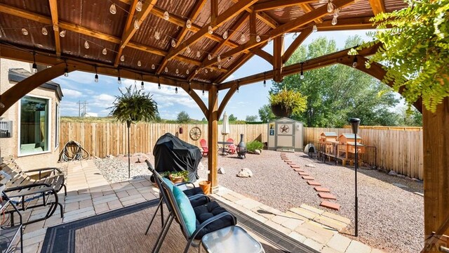 view of patio / terrace featuring a fenced backyard, a storage shed, an outdoor structure, outdoor dry bar, and a gazebo