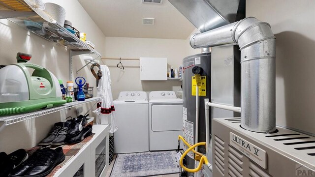 washroom with laundry area, washer and clothes dryer, gas water heater, and visible vents