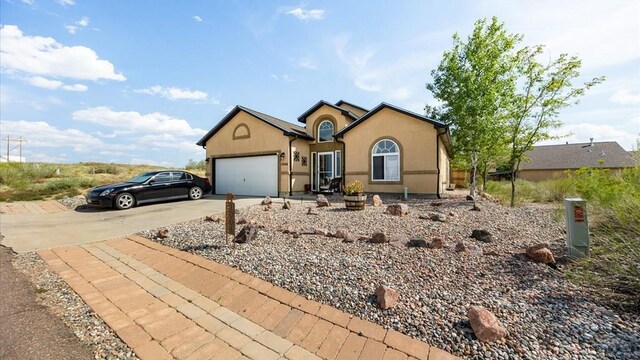 single story home with a garage, concrete driveway, and stucco siding