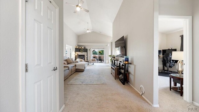 corridor with baseboards, high vaulted ceiling, and light colored carpet