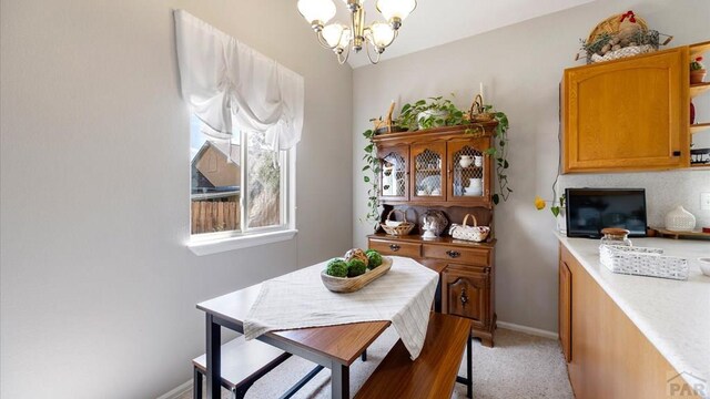 dining space with light carpet, baseboards, and a notable chandelier