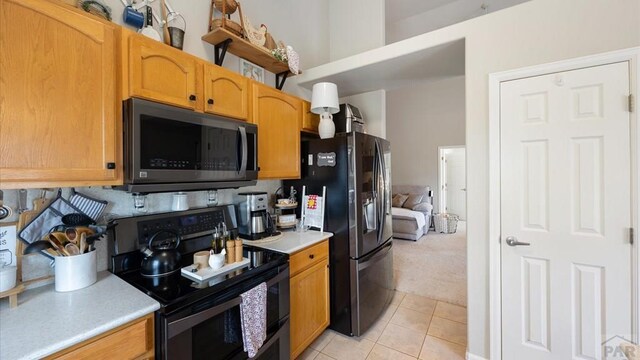 kitchen with stainless steel appliances, light tile patterned flooring, light countertops, and light colored carpet