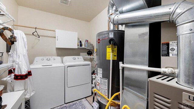 laundry area featuring gas water heater, heating unit, visible vents, washing machine and dryer, and laundry area