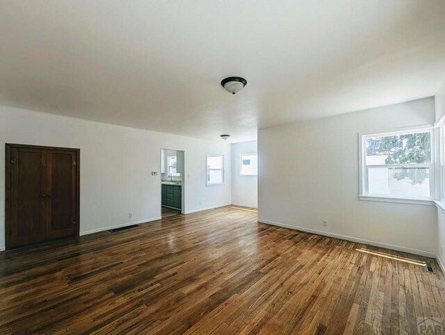 unfurnished room with visible vents, dark wood finished floors, and baseboards