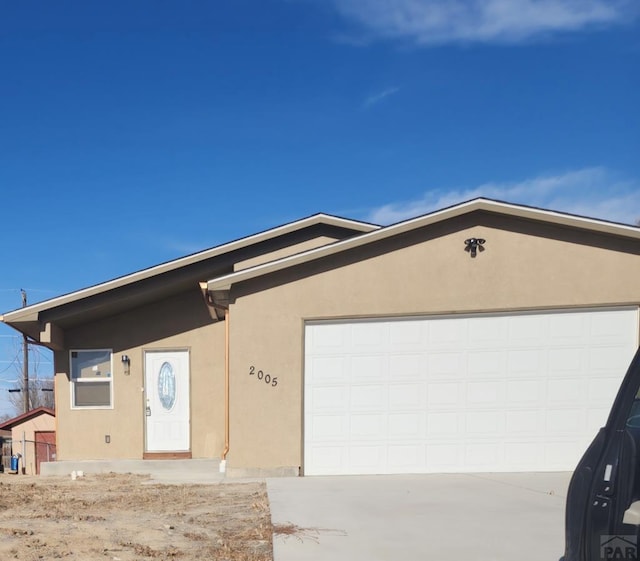 single story home featuring concrete driveway, an attached garage, and stucco siding