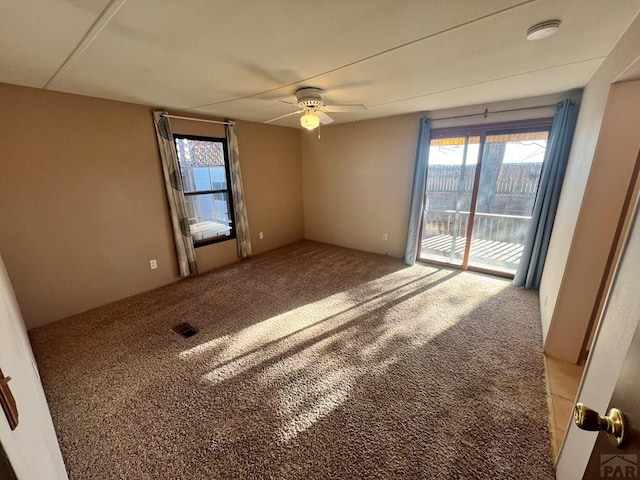 carpeted spare room with a healthy amount of sunlight and a ceiling fan