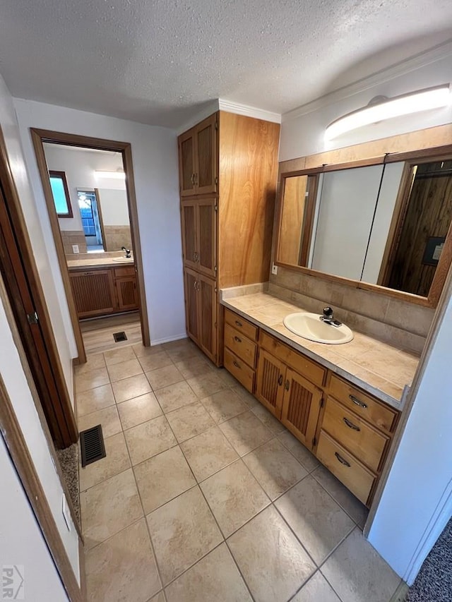 bathroom with a textured ceiling, tile patterned floors, visible vents, vanity, and decorative backsplash