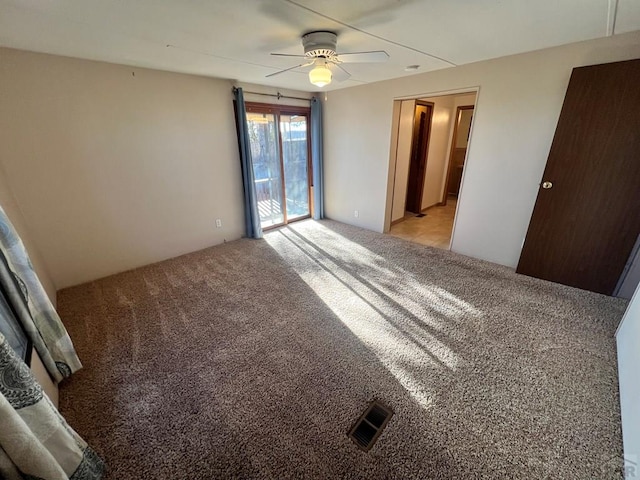 empty room featuring a ceiling fan, light colored carpet, and visible vents