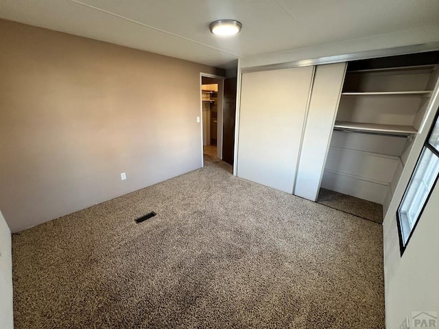 unfurnished bedroom featuring a closet, carpet flooring, and visible vents