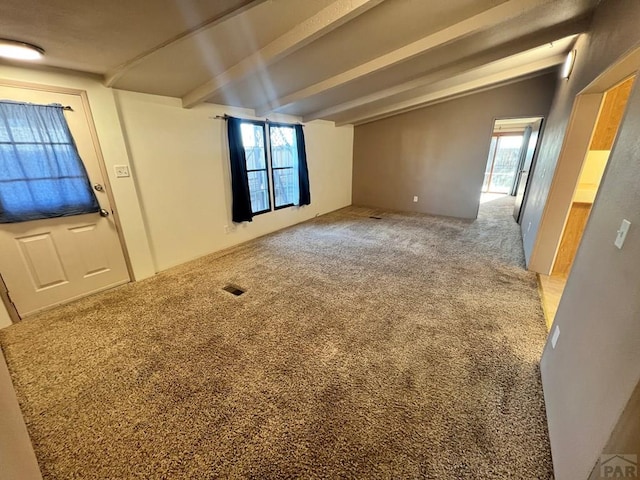 carpeted spare room featuring lofted ceiling with beams, visible vents, and a wealth of natural light