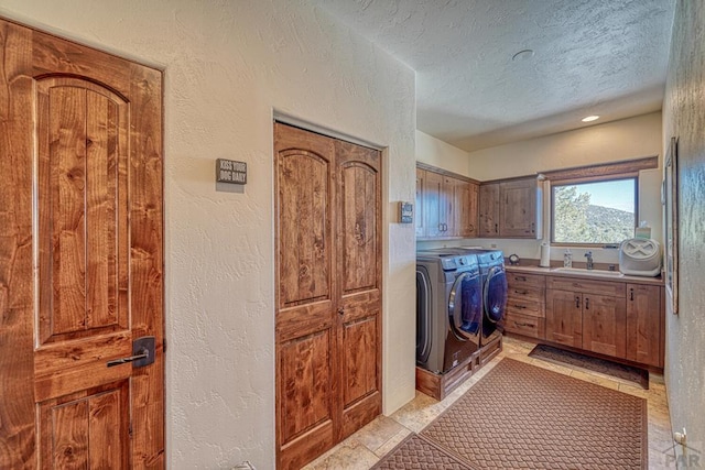 clothes washing area featuring a textured wall, independent washer and dryer, a sink, and cabinet space