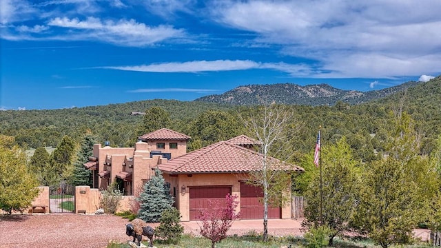 view of front facade featuring an attached garage, a mountain view, a tile roof, a gate, and stucco siding