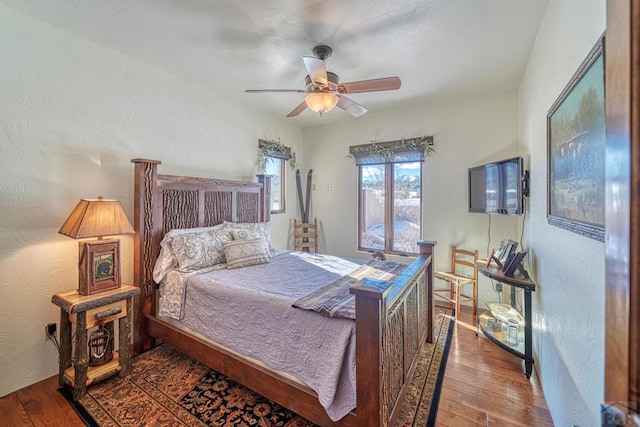 bedroom with a ceiling fan, a textured wall, and wood finished floors