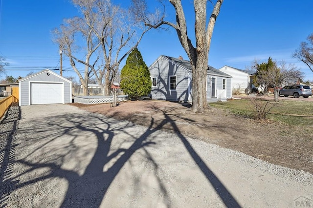 view of home's exterior featuring a detached garage, an outdoor structure, driveway, and fence