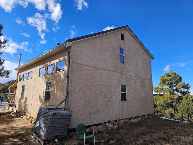 view of side of home featuring fence and stucco siding