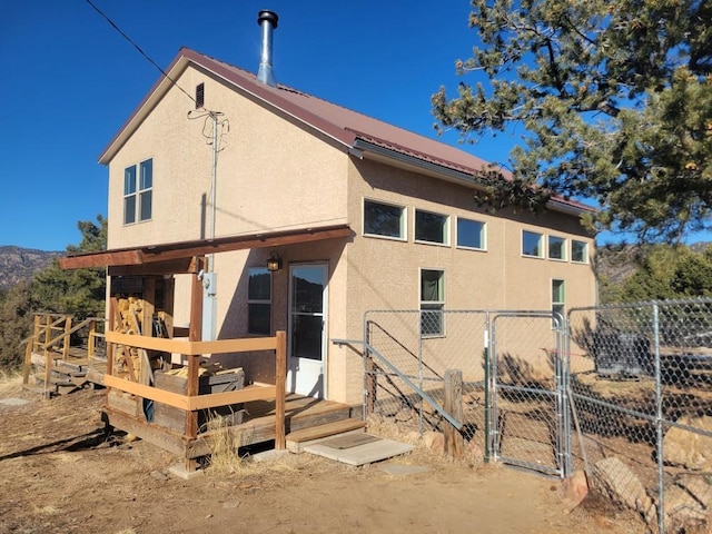 back of property with a gate, fence, and stucco siding