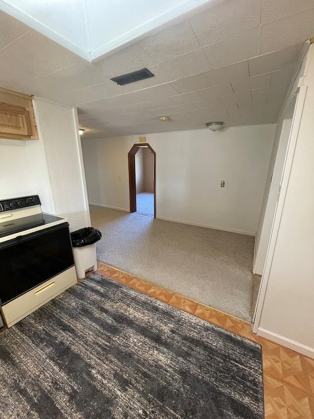 kitchen with electric range oven, baseboards, arched walkways, and light brown cabinets