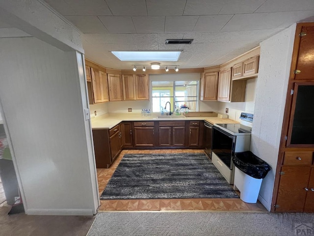 kitchen featuring a sink, a skylight, light countertops, and white range with electric cooktop