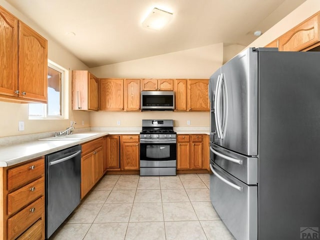 kitchen featuring lofted ceiling, stainless steel appliances, light countertops, a sink, and light tile patterned flooring