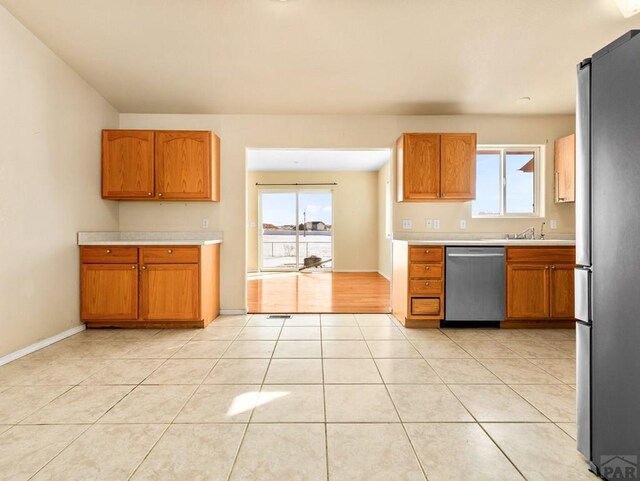 kitchen featuring light tile patterned floors, plenty of natural light, stainless steel appliances, and light countertops