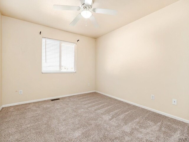 empty room featuring a ceiling fan, carpet flooring, visible vents, and baseboards