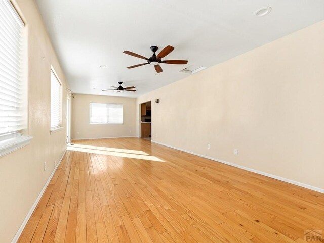 unfurnished living room with baseboards, ceiling fan, and light wood finished floors