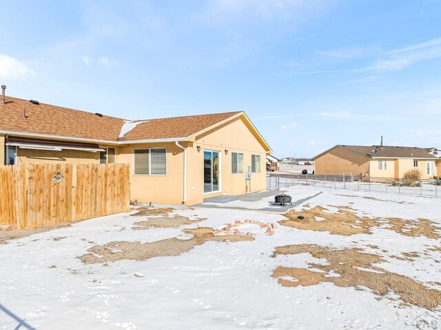 snow covered house with fence and stucco siding