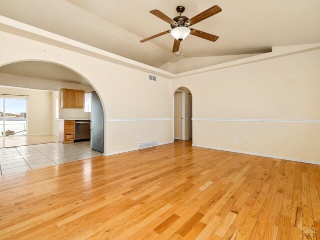 spare room featuring light wood-style floors, visible vents, and arched walkways