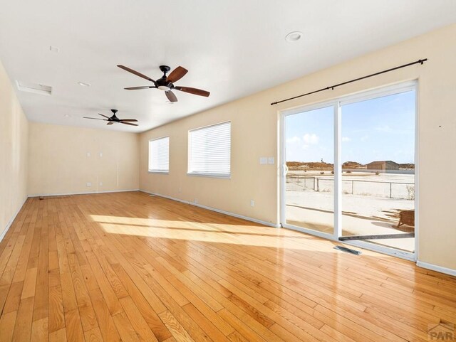 unfurnished living room featuring light wood-style floors, visible vents, ceiling fan, and baseboards