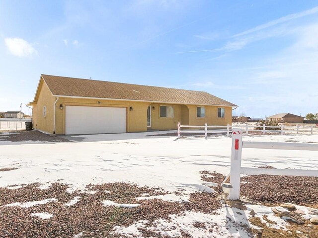 view of front of property featuring an attached garage, fence, and stucco siding