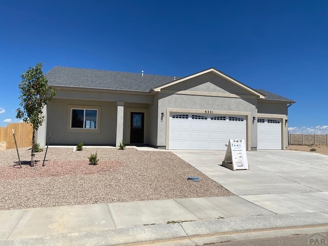 ranch-style home with a garage, a shingled roof, fence, driveway, and stucco siding