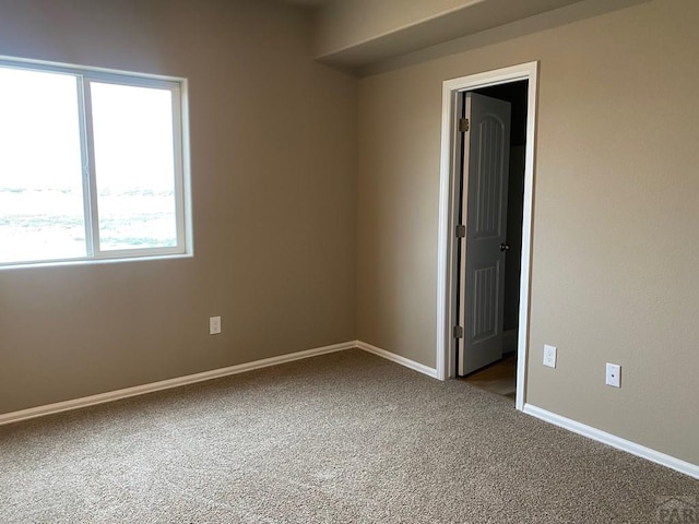 unfurnished room with carpet and baseboards