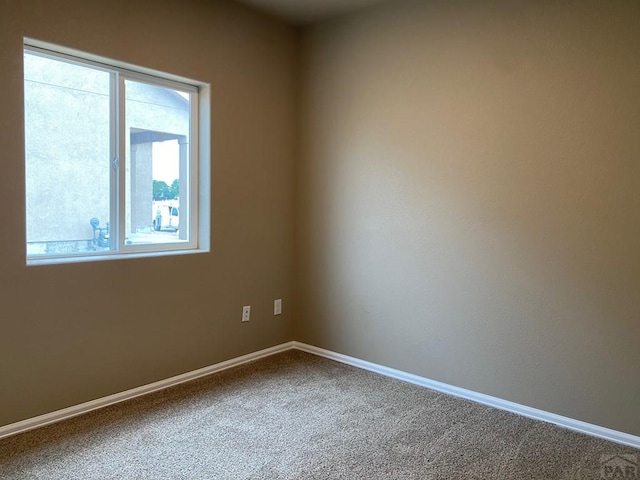 spare room featuring carpet flooring and baseboards