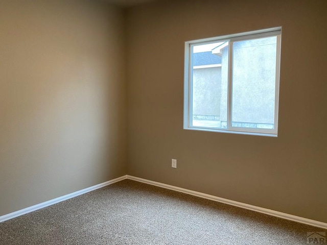 unfurnished room featuring carpet and baseboards