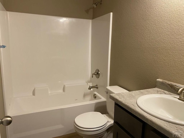 full bath featuring a textured wall, tub / shower combination, vanity, and toilet