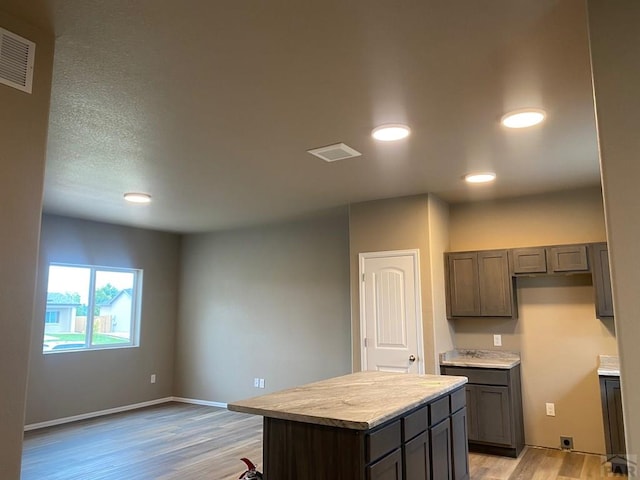 kitchen with visible vents, baseboards, light wood-style floors, light countertops, and a center island