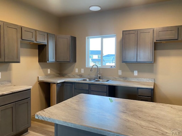 kitchen with light countertops, light wood-type flooring, and a sink