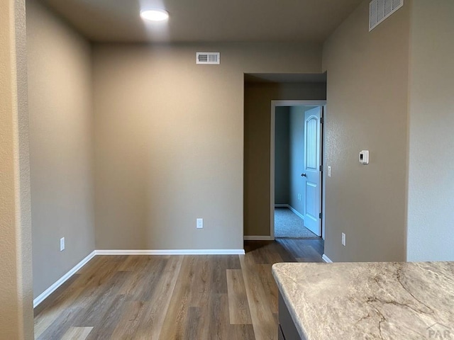 unfurnished bedroom featuring wood finished floors, visible vents, and baseboards