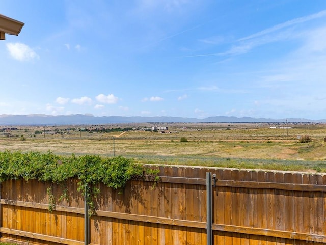 view of yard featuring a rural view, a mountain view, and fence