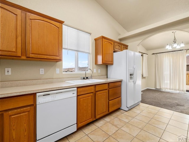 kitchen featuring light countertops, hanging light fixtures, vaulted ceiling, a sink, and white appliances