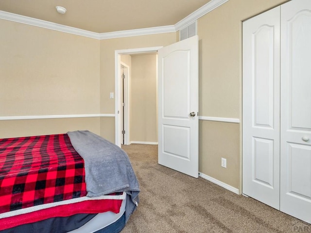 carpeted bedroom with baseboards, ornamental molding, and a closet