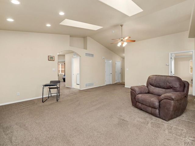 living area featuring arched walkways, lofted ceiling with skylight, carpet flooring, and visible vents