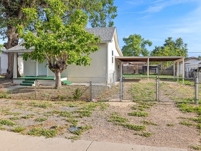 view of property exterior with a gate, fence, a carport, and roof with shingles