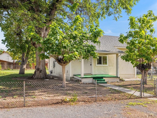 obstructed view of property with roof with shingles, fence, and stucco siding