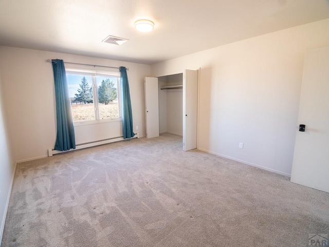 unfurnished bedroom featuring a baseboard heating unit, a closet, visible vents, and carpet flooring