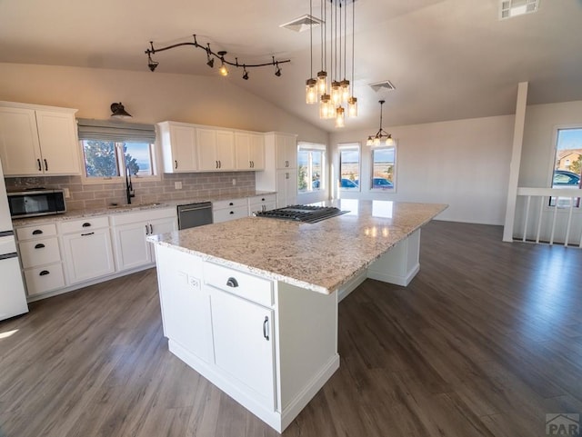 kitchen with a center island, stainless steel microwave, visible vents, a sink, and dishwasher