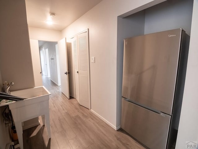 hall with light wood-type flooring and baseboards